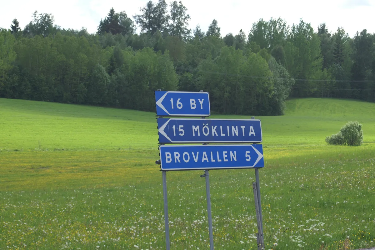 Landsväg med vägskyltar vid en åker på svensk landsbygd